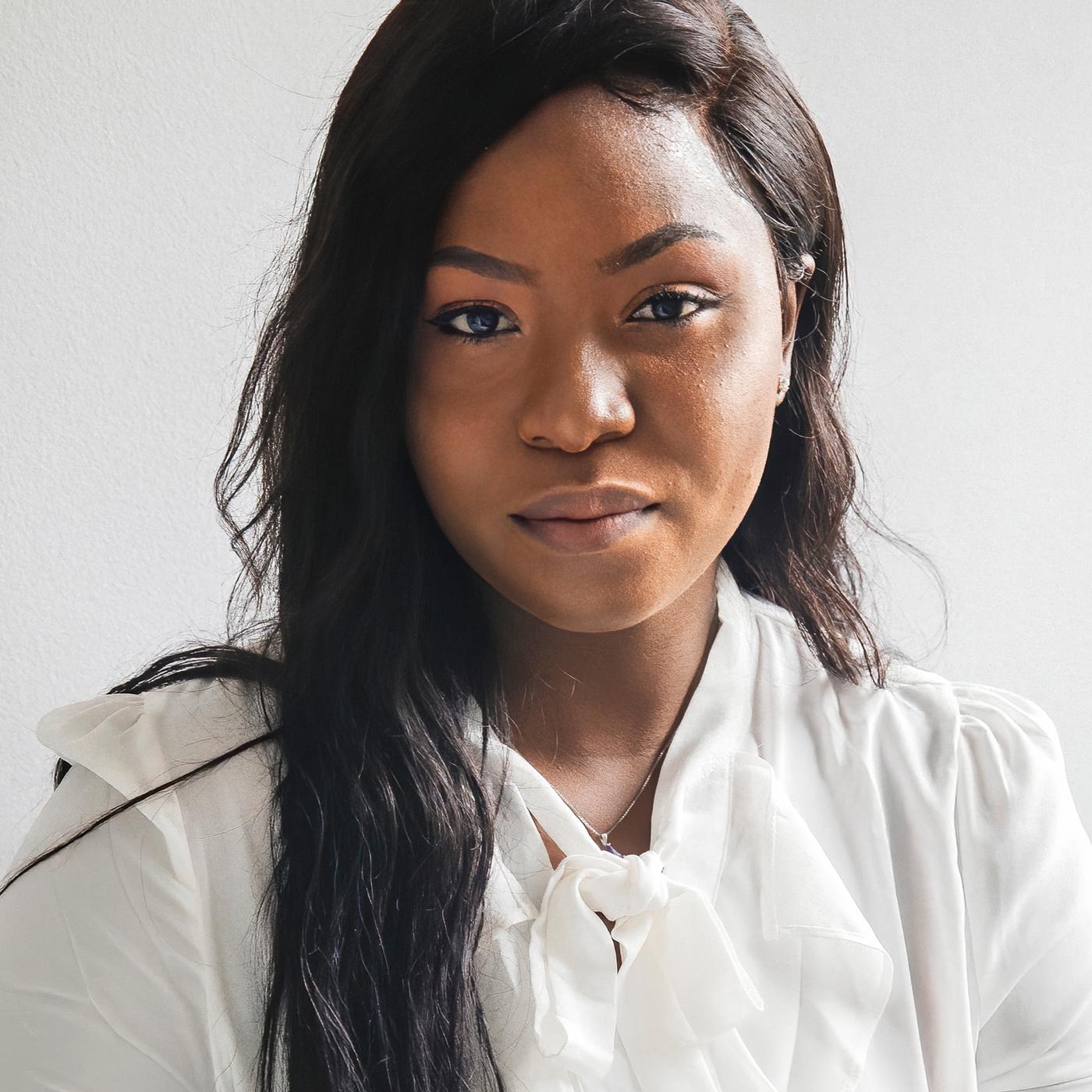 A portrait of Precious, a Nigerian refugee and IKEA Canada co-worker, wearing a white shirt against a white background.