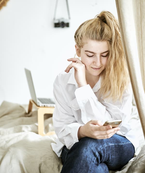 A portrait of Yvet sitting on her bed.