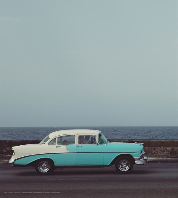 A print of a vintage car on a road.