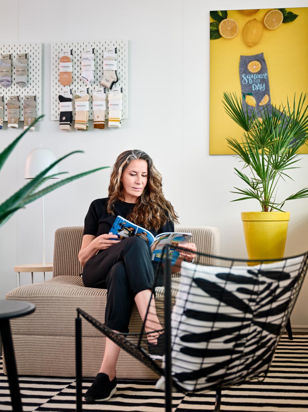 A professional‑looking woman sitting on a sofa reading a magazine