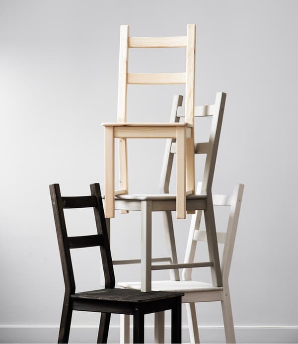 A pyramid of IKEA IVAR chairs, each varnished or stained a different colour.