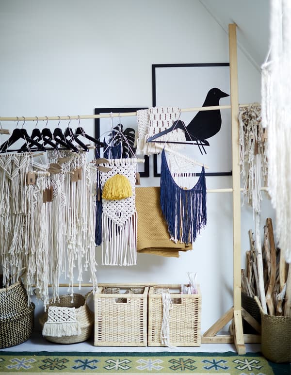 A rail-hanger storage system filled with hanging home-made macramé crafts.