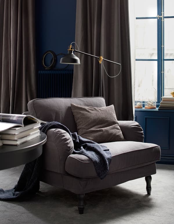 A reading area with an armchair, floor lamp and table.