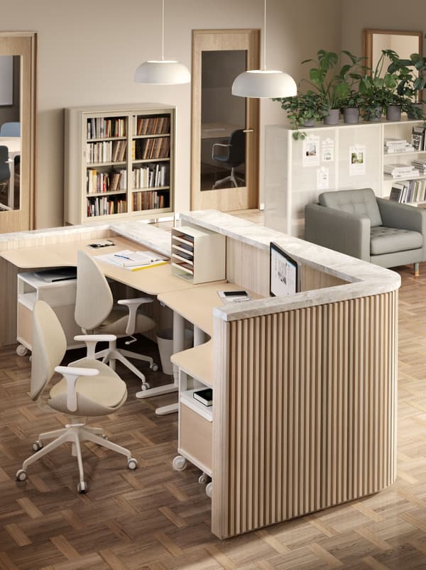 A reception desk made from two BEKANT desks with two HATTEFJÄLL chairs and two BEKANT storage units on castors behind it.