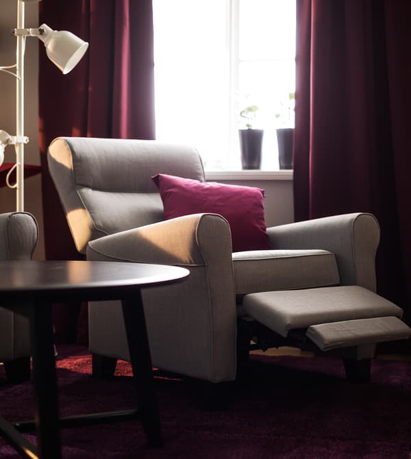 A reclining chair and coffee table sit in front of a window.