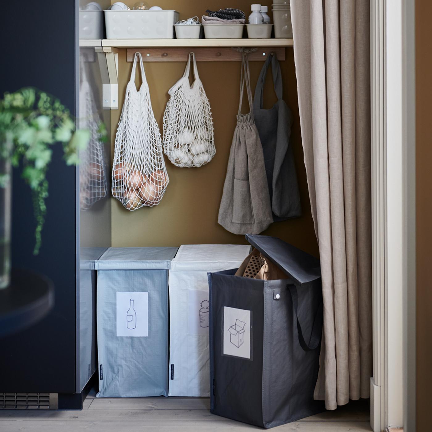 A recycling station with three DIMPA waste-sorting bags, shelves and KUNGSFORS net bags placed in a recess behind a curtain.