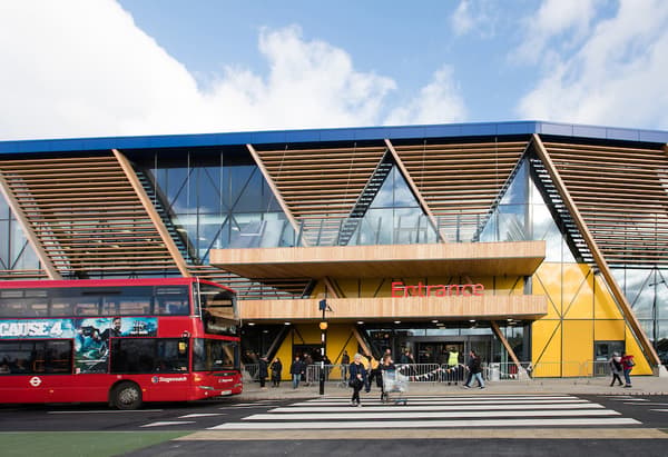 A red bus drives past the new IKEA Greenwich store in London with wooden and glass frontage.