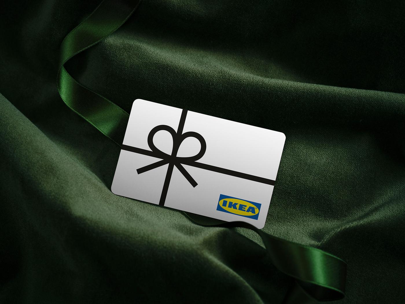 A red IKEA gift card with a graphic of a ribbon and IKEA logo on the green velvet sheet.