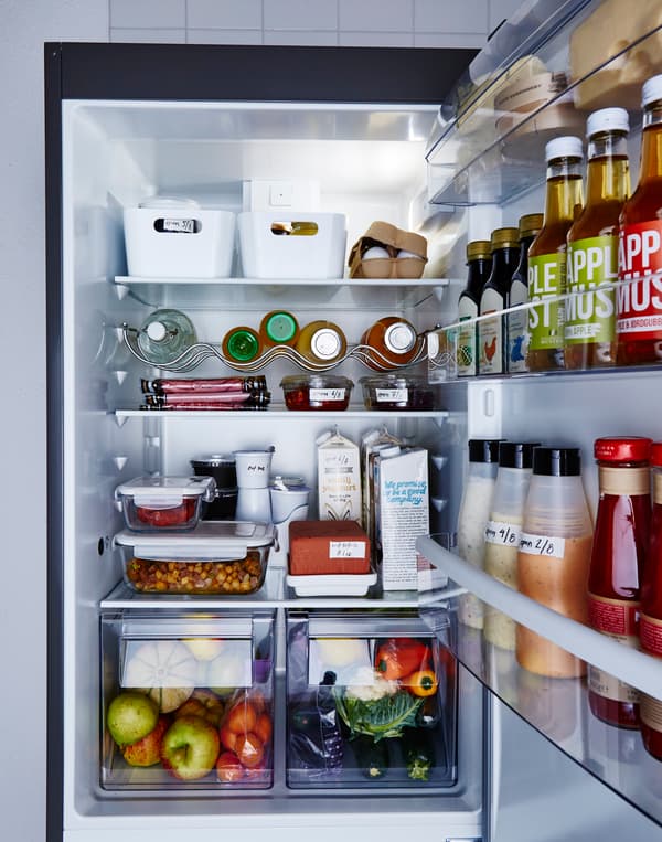 A refrigerator is neatly organized with food sorted neatly into clear or labeled containers.