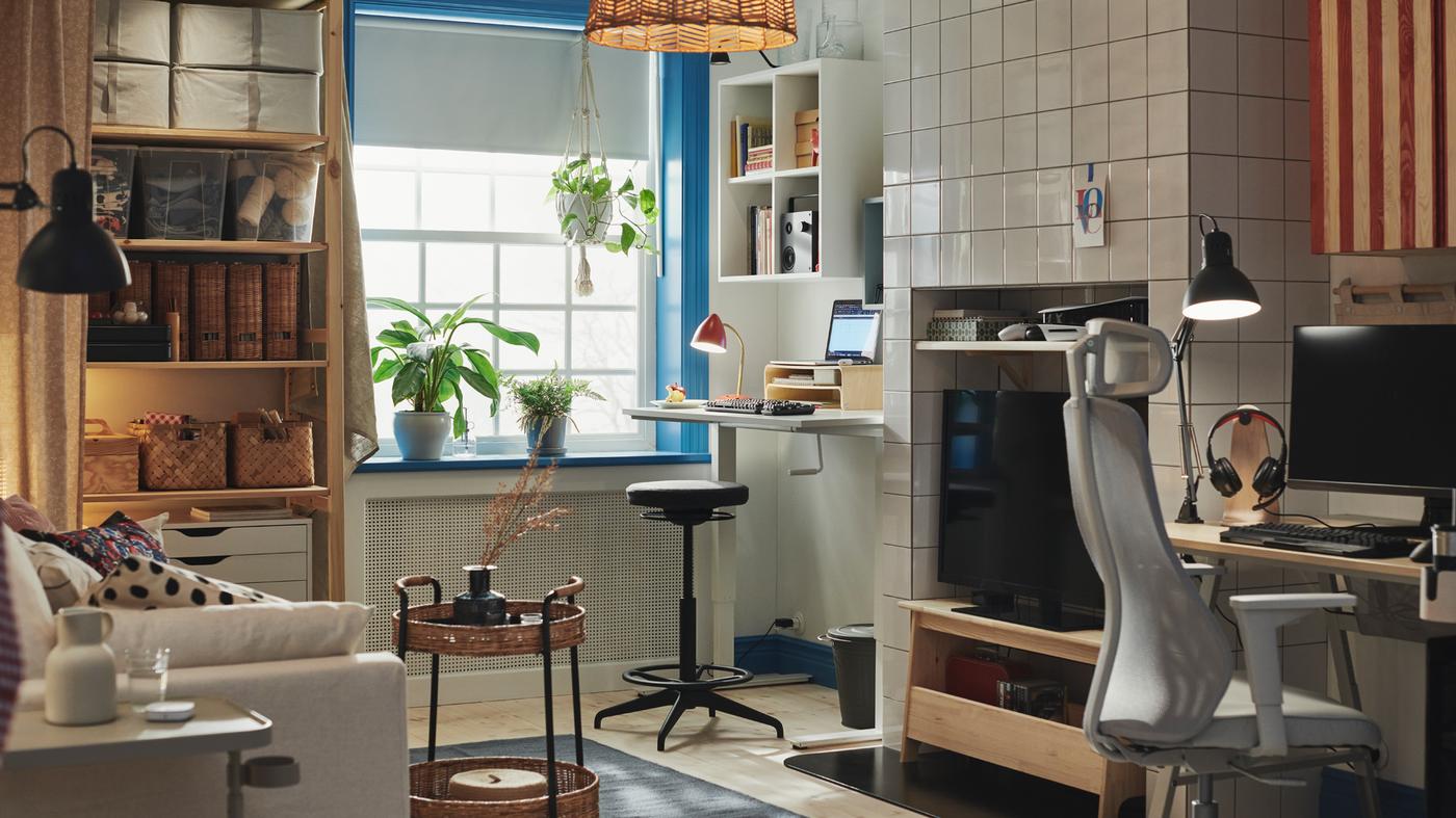 A room at home with a dark gray LIDKULLEN active sit/stand support standing at a TROTTEN sit/stand desk next to a window.