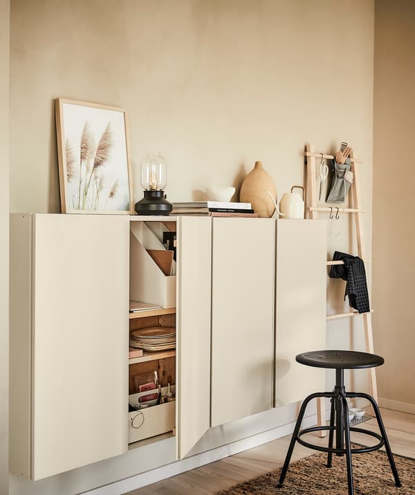 A room interior themed entirely with the colour of blond wood: wall panel, wall cupboards, rug and decorations; black stool.