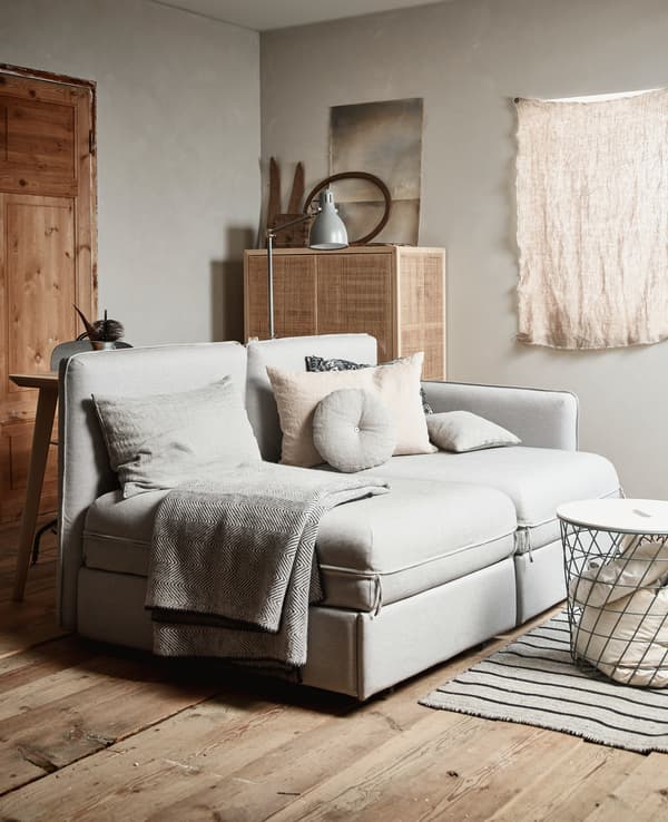 A room with a natural coloured sofa, storage basket and storage cabinet in the background.