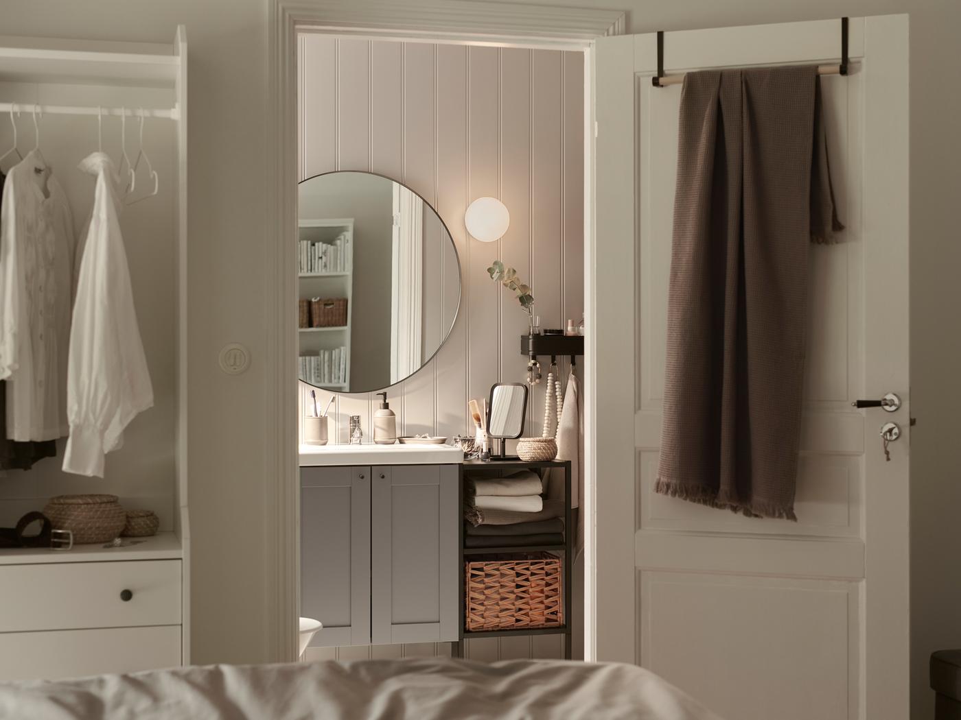 A room with an open door with, STAJLIG hangers, and a VALLASÅN bath towel in light grey/brown hanging and a bathroom mirror.