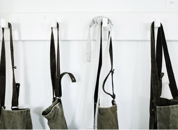 A row of white hooks that are holding Annika’s aprons for her pottery studio.