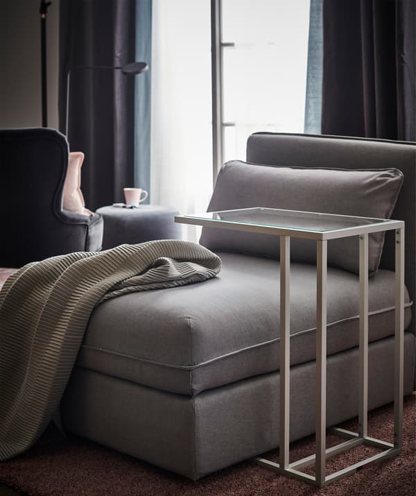 A seating module in grey with a nearby laptop stand.