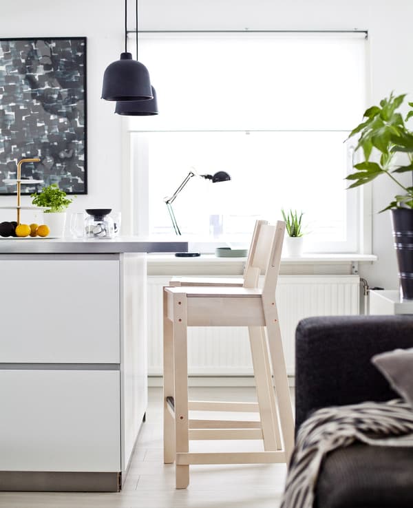 A section of white kitchen island with a pale-wood stool.