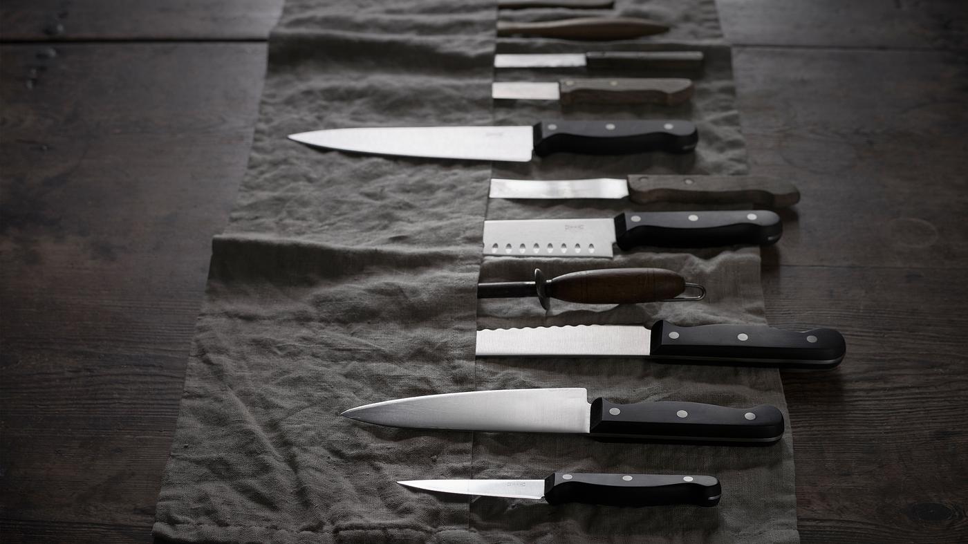 A selection of VARDAGEN kitchen knives in various sizes laying on a dark-grey knife roll.