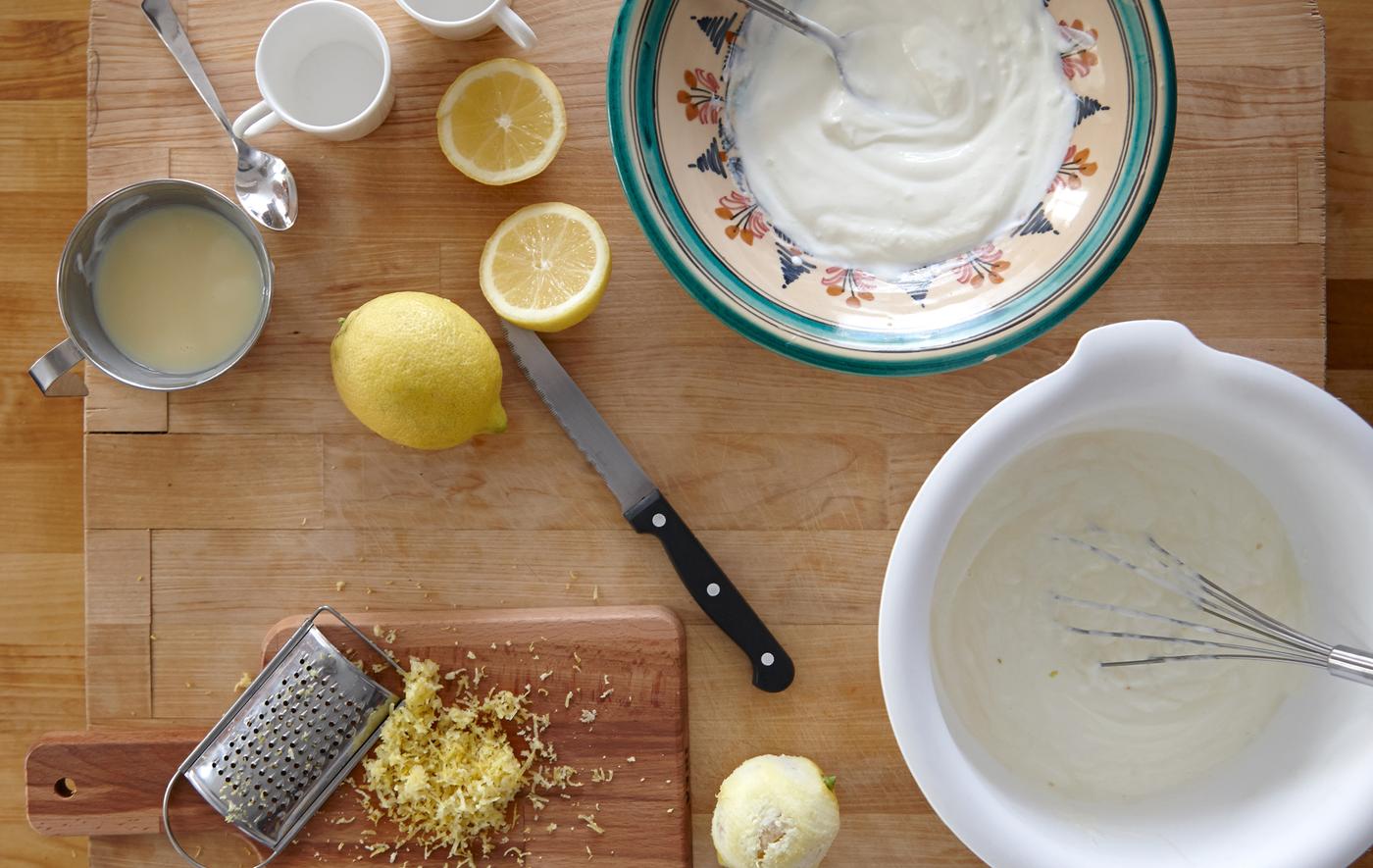 A set of ingredients for lemon mousse, including lemon rind, juice, yogurt and condensed milk.