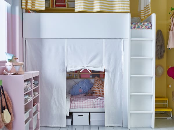A shared kids’ room at night with a loft bed and a bed underneath that has a privacy curtain.