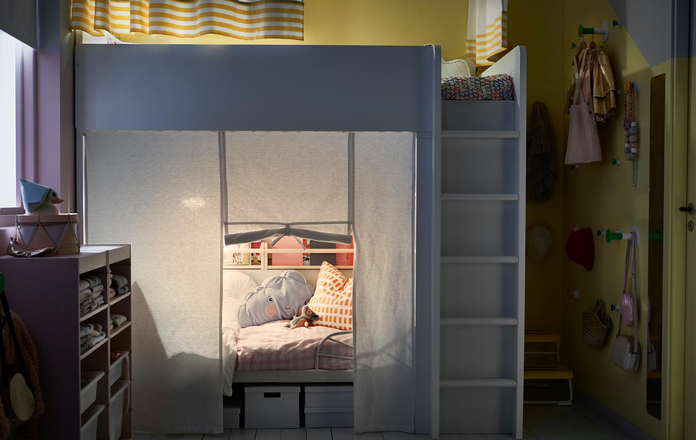 A shared kids’ room with a loft bed and an extendable space in the space below with privacy curtains around each bed.