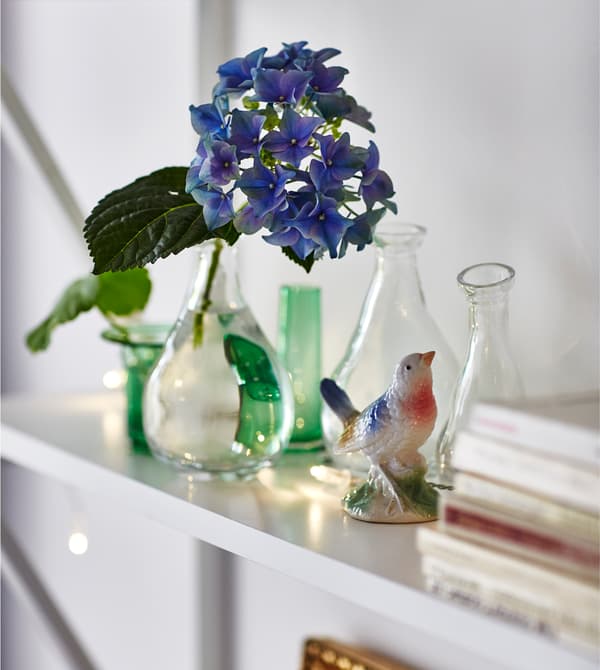 A shelf is decorated with small glass vases and a figurine of a bird.