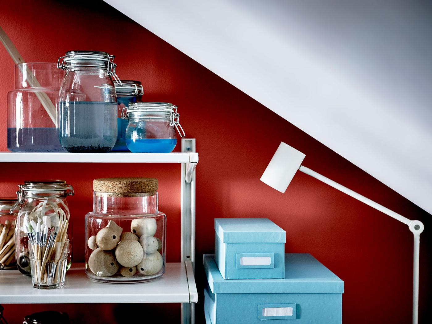 A shelving unit is stocked with crafting supplies and sits beneath a sloped ceiling.
