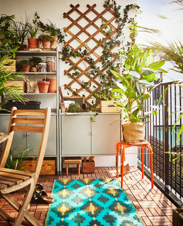 A shelving unit sits on a balcony to create storage and a workspace for gardening.