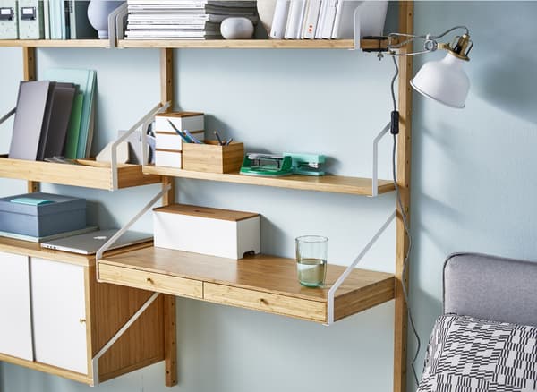 A shelving unit that includes an office desk station, mounted onto a blue living room wall.