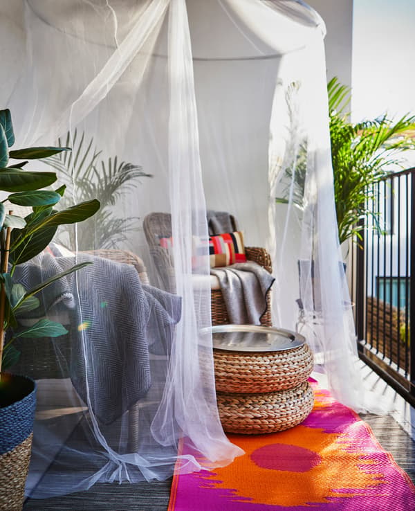 A sitting area with two cosy armchairs and a small table are given privacy with a canopy hung above.