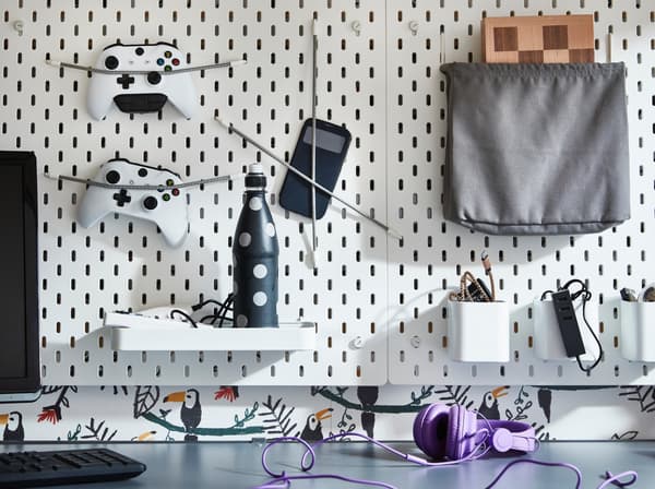 A SKADIS pegboard with gaming equipment attached with bungee cords