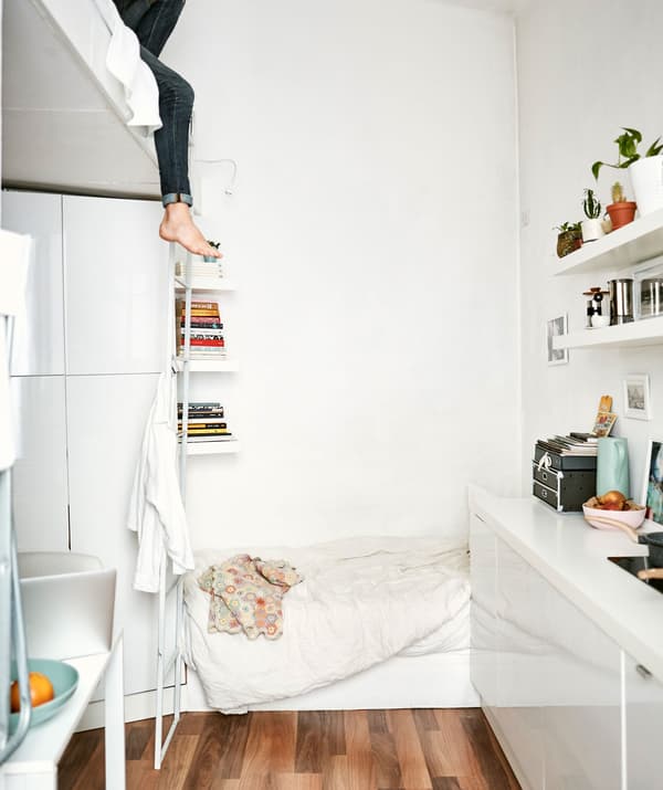 A small all-white apartment with a day bed, mezzanine level and one-wall kitchen.