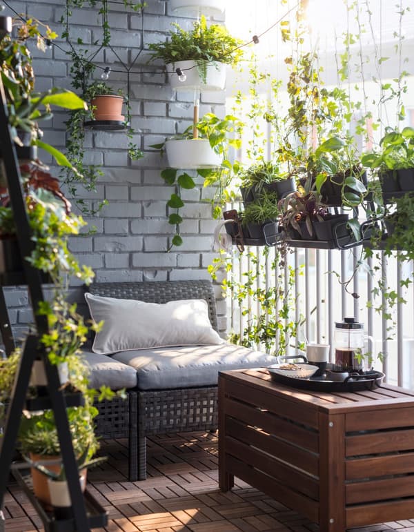 A small balcony with outdoor seating, a low bench, a flower box and plant pots.