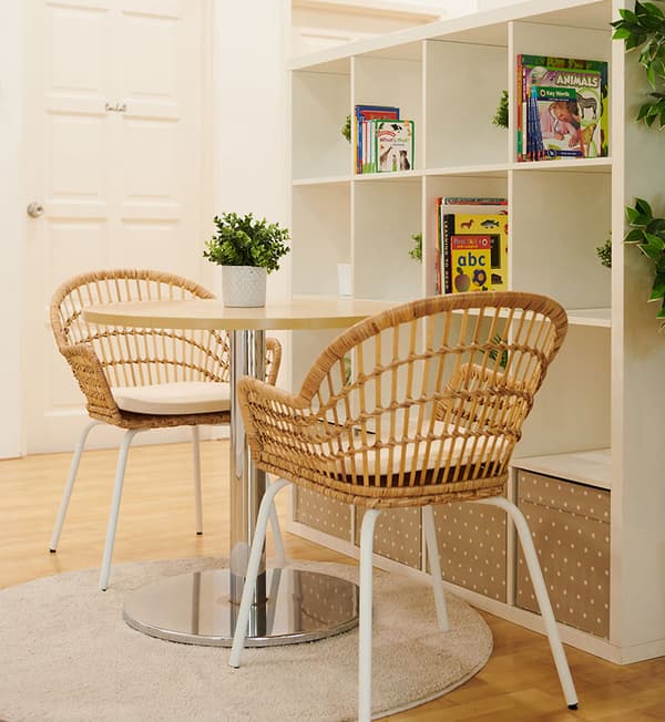 A small circular table with two chairs on top a light grey rug.