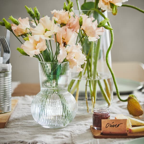 A small clear vase is filled with freshly cut flowers on a wedding table