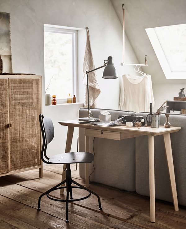 A small desk and chair, placed directly before a sofa bed.