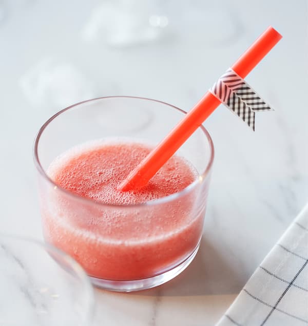 A small glass with a straw is filled with a smoothie.