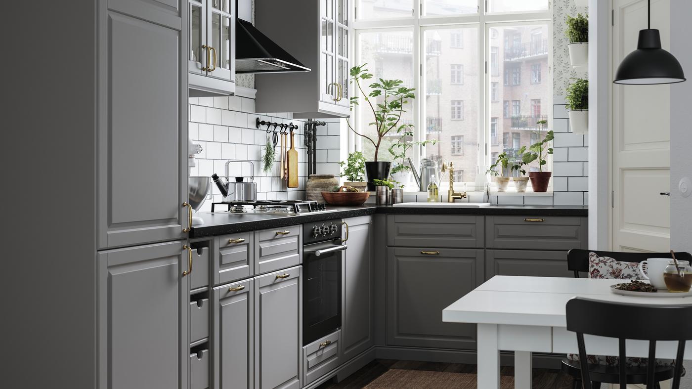 A small kitchen with grey kitchen cabinets, a black mineral-effect worktop, a white sink with a visible front and a gas hob.