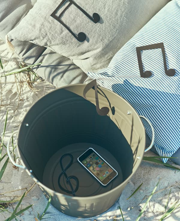 A smartphone sits in a bucket to create a DIY speaker.