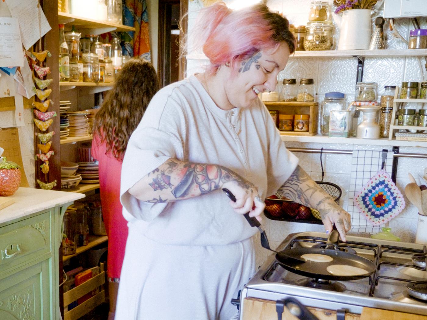 A smiling woman is making pancakes in a HEMLAGAD pancake pan on the stove.
