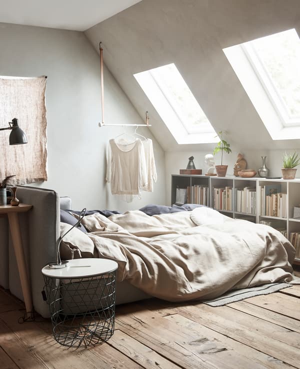 A sofa bed is extended and made up with neutral coloured bed linens.