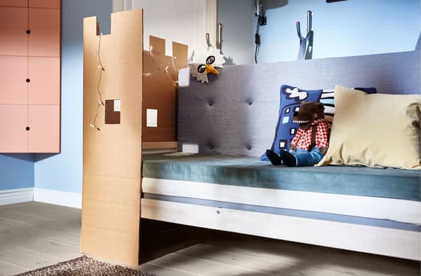 A sofa made from mattresses with cushions and a playful cardboard wall