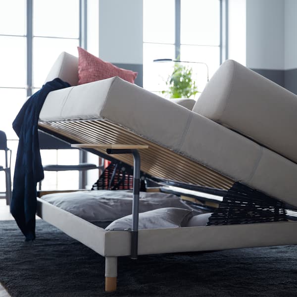 A sofabed raised to reveal bedding storage underneath. 