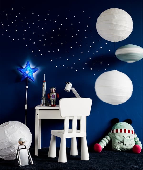 A space-inspired work spot. An IKEA SUNDVIK white children’s desk with space decorations and dark blue walls