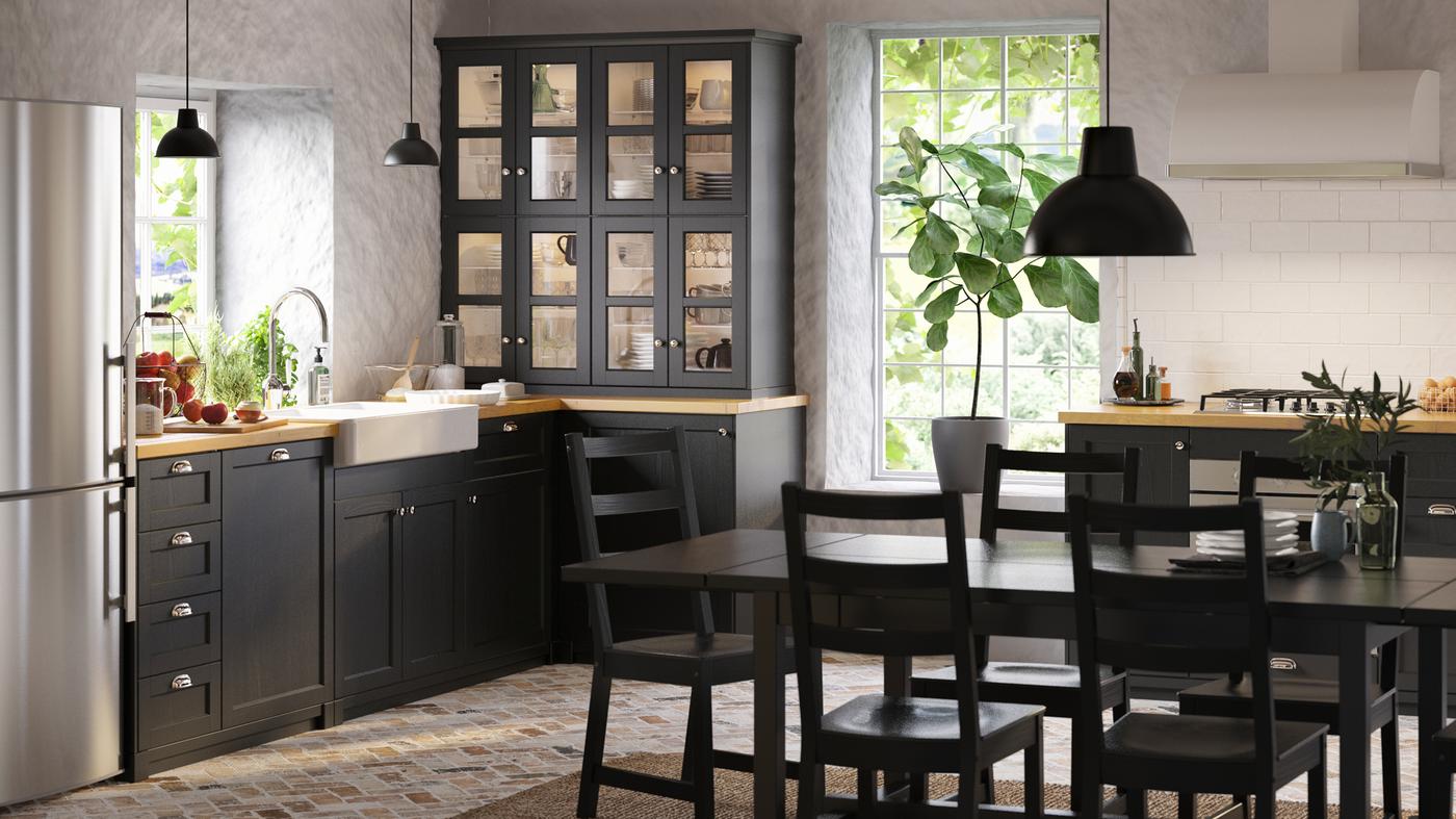 A spacious black and white kitchen in a classic style with stained black cabinet doors, white worktops, and an island.