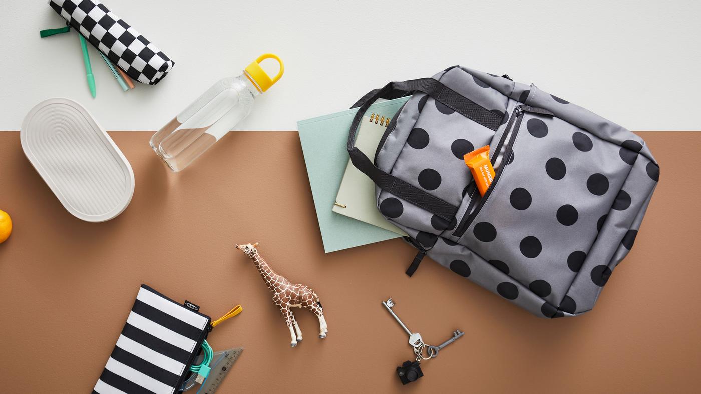 A STARTTID backpack lays next to a FORMSKÖN waterbottle and HALVVARM food container, SKÖRDA accessory bag and other items.