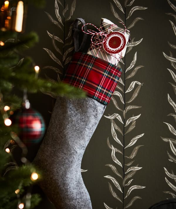 A stocking hanging on the wall, with a present and an IKEA VINTER gift tag peeking out of the top.