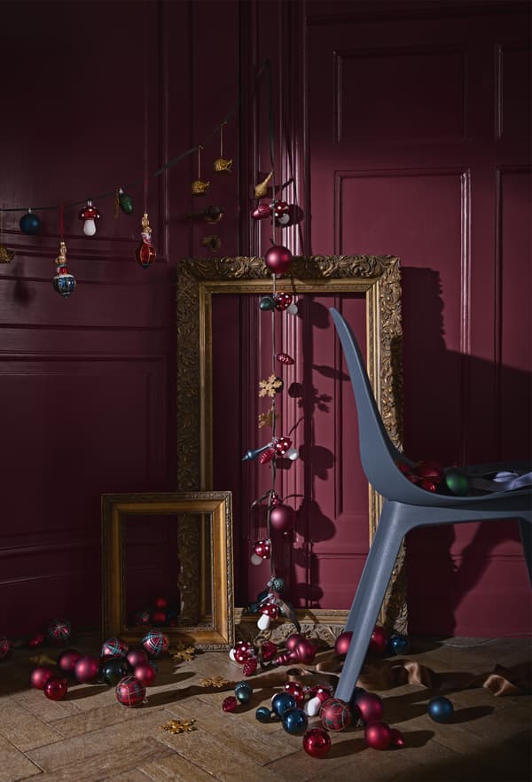 A string of tree decorations and lighting in a room with a chair and gold photo frames.