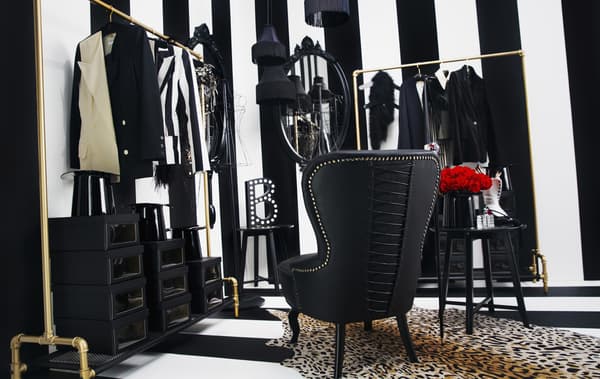 A striped dressing room with clothes racks, an armchair and clothes storage.