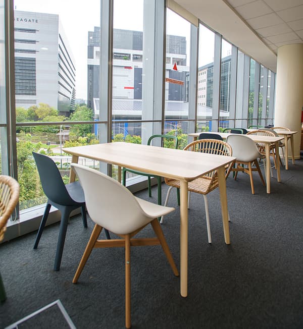 A study area featuring multiple wooden tables, blue, and white chairs.