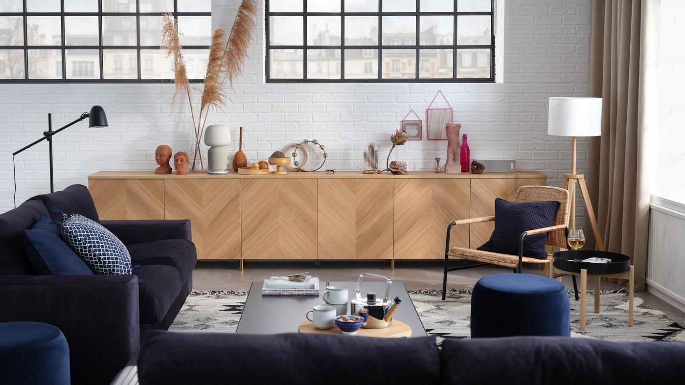 A stylish living room with a 3-seat sofa, a 2-seat sofa-bed, storage combination with doors, and an armchair.